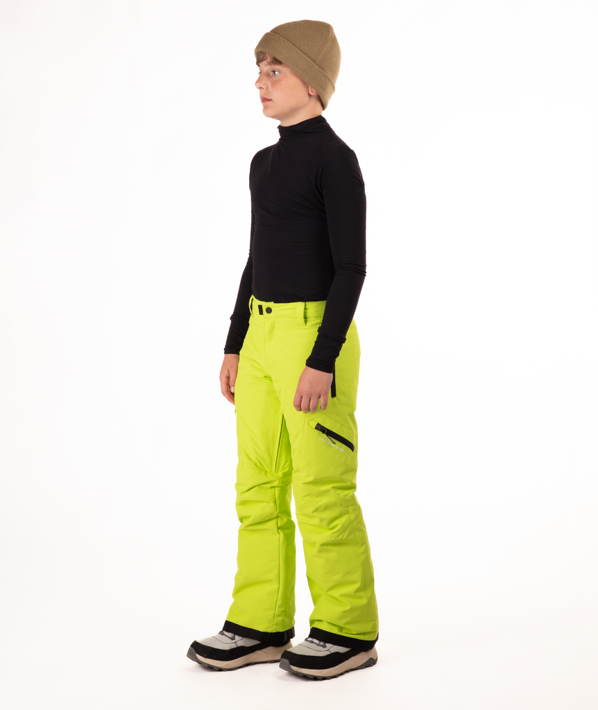 youth boy wearing a black long-sleeve shirt and bright green snow pants on a white background
