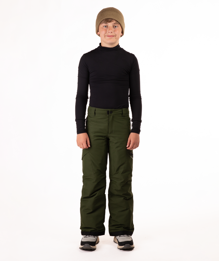 youth boy wearing a black long-sleeve shirt and green snow pants on a white background