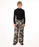 youth boy wearing a black long-sleeve shirt and camouflage snow pants on a white background