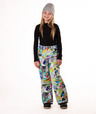 Girl wearing multi colored geometric patterned snow pants and a black top on a white background