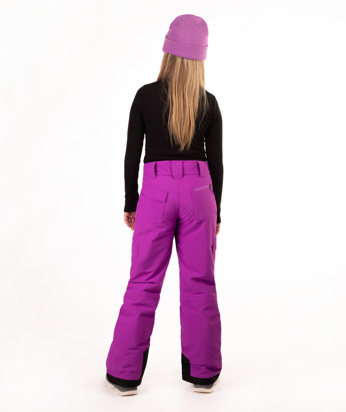 A model shown from the back wearing bright purple snow pants, a black long-sleeve top, and a matching purple beanie against a white studio background.