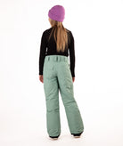 back of a girl wearing green snow pants and a black long-sleeve top on a white background