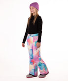 girl wearing multi color pastel abstract print snow pants and a black long-sleeve top on a white background