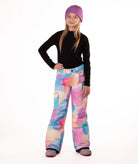 girl wearing multi color pastel abstract print snow pants and a black long-sleeve top on a white background
