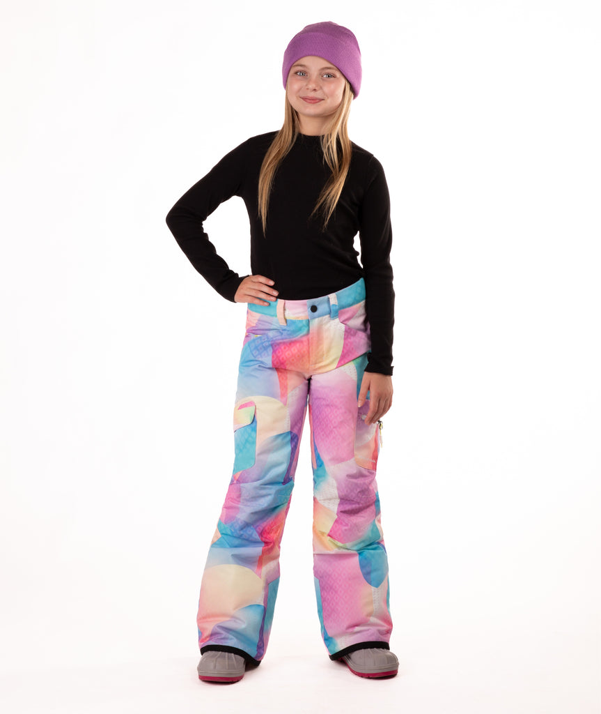 girl wearing multi color pastel abstract print snow pants and a black long-sleeve top on a white background