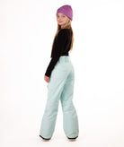 back of a girl wearing light blue snow pants and a black long-sleeve top on a white background