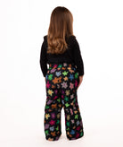 back of child wearing a multi color flower print snow bib with black top on a white background