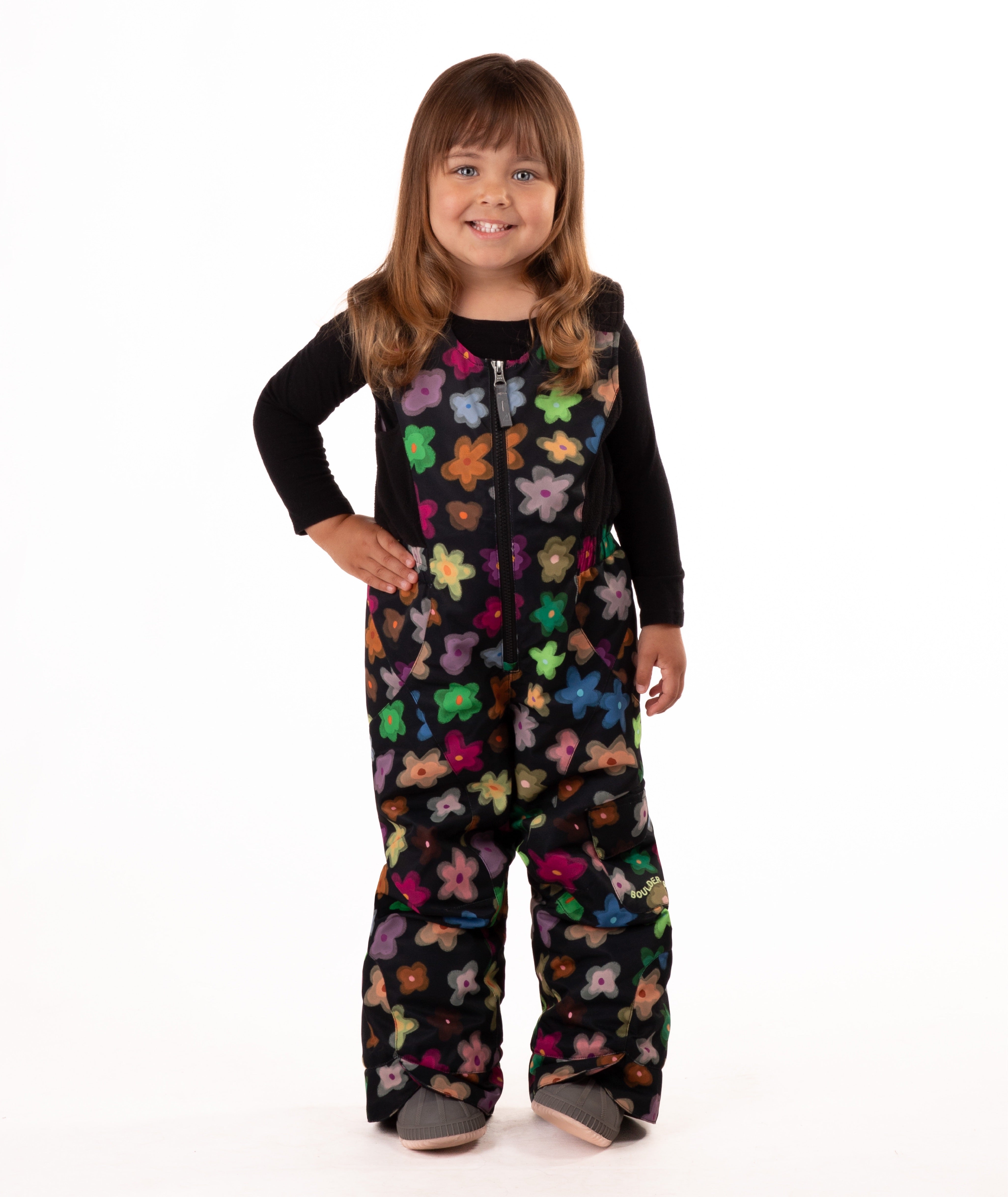 child wearing a multi color flower print snow bib with black top on a white background