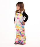 child wearing a multi color abstract print snow bib with black top on a white background