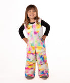 child wearing a multi color abstract print snow bib with black top on a white background