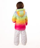 back of a child wearing a colorful gradient jacket and white pants on a white background