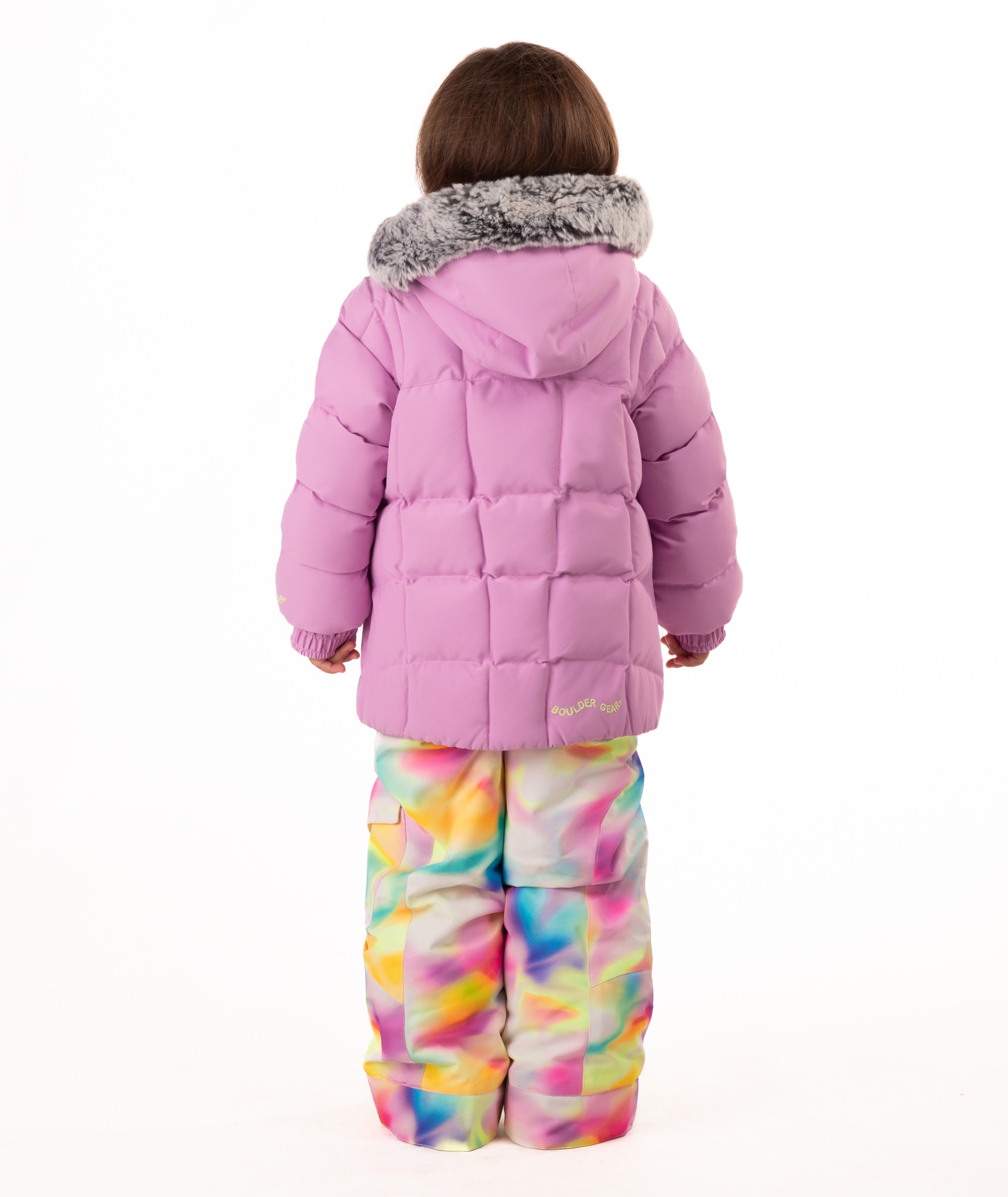 Child wearing a pink quilted puffy winter coat on a white background
