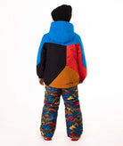 A young child wearing a color-blocked ski jacket in blue, red, black, and orange, paired with patterned snow pants and a black beanie, standing against a white studio background.