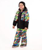 A child wearing a colorful camouflage ski jacket and matching pants with a black beanie, standing against a plain white background.