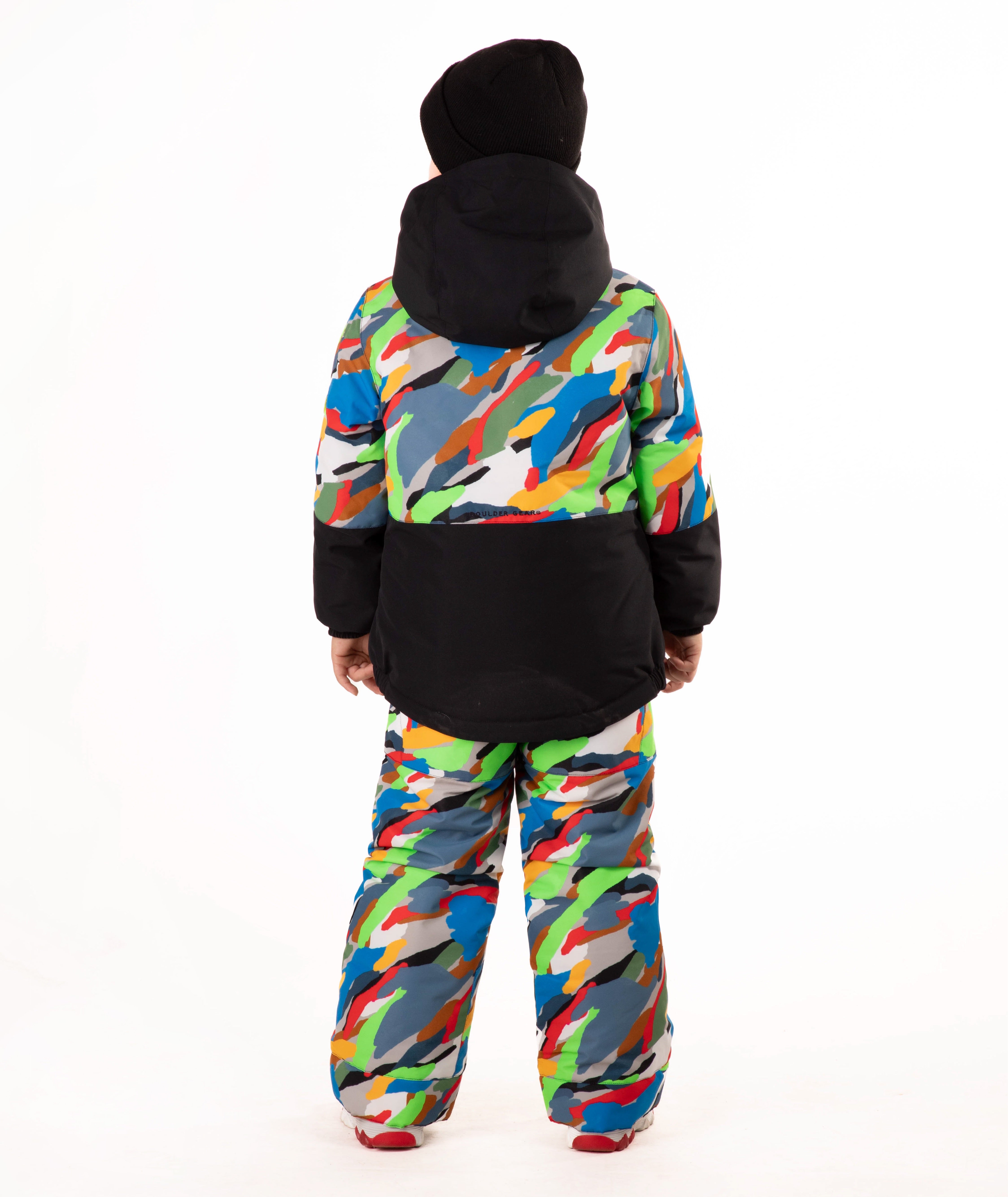 A child wearing a colorful camouflage ski jacket and matching pants with a black beanie, standing against a plain white background.