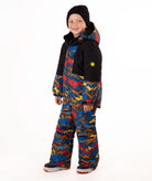 A child wearing a colorful mountain pattern ski jacket and matching pants with a black beanie, standing against a plain white background.