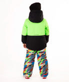 A child wearing a bright neon green and black ski jacket with colorful camouflage snow pants, a black beanie, and ski boots, standing against a plain white background.
