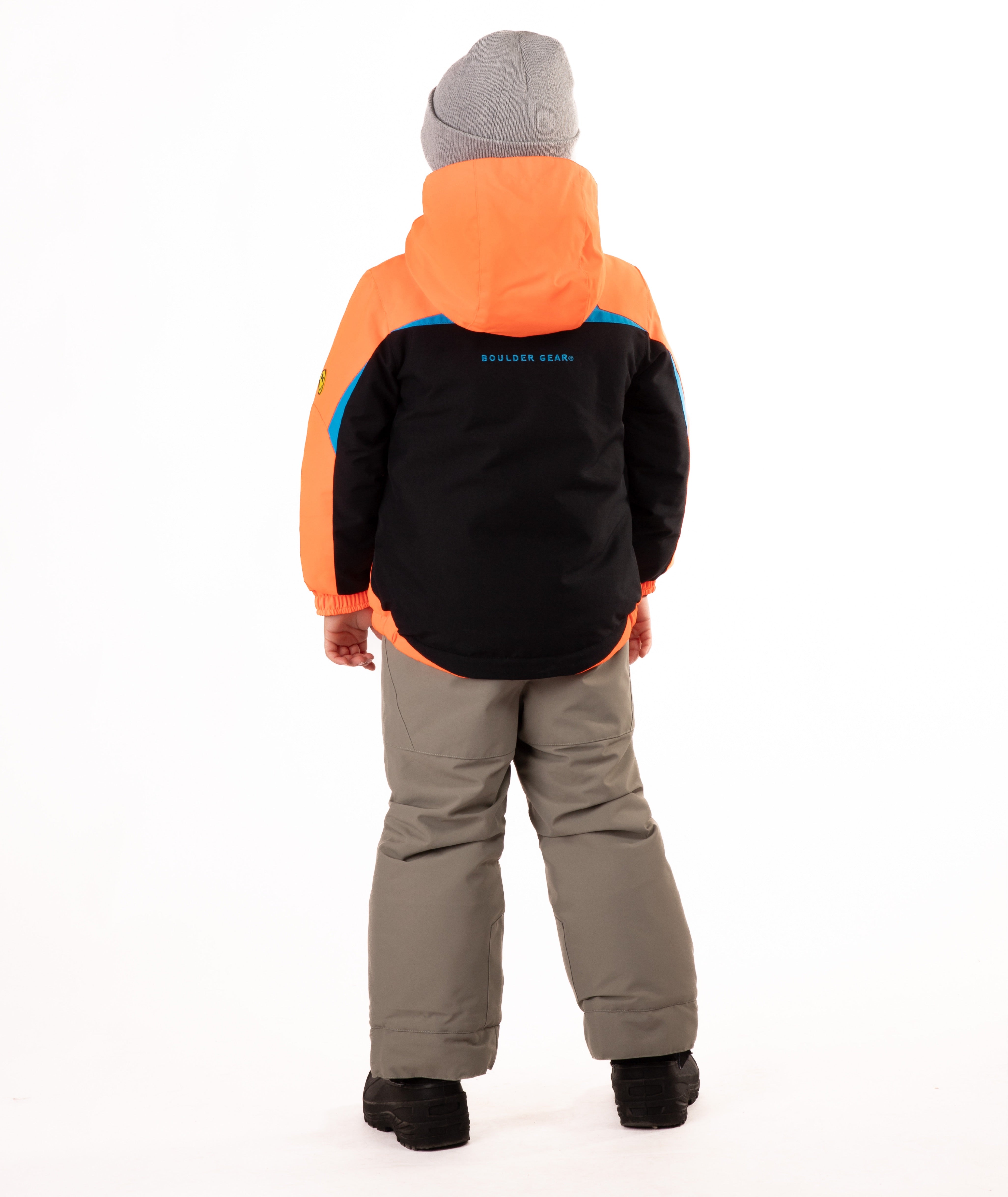 A child wearing an orange and black jacket with a visible brand logo on the back, standing against a white background.