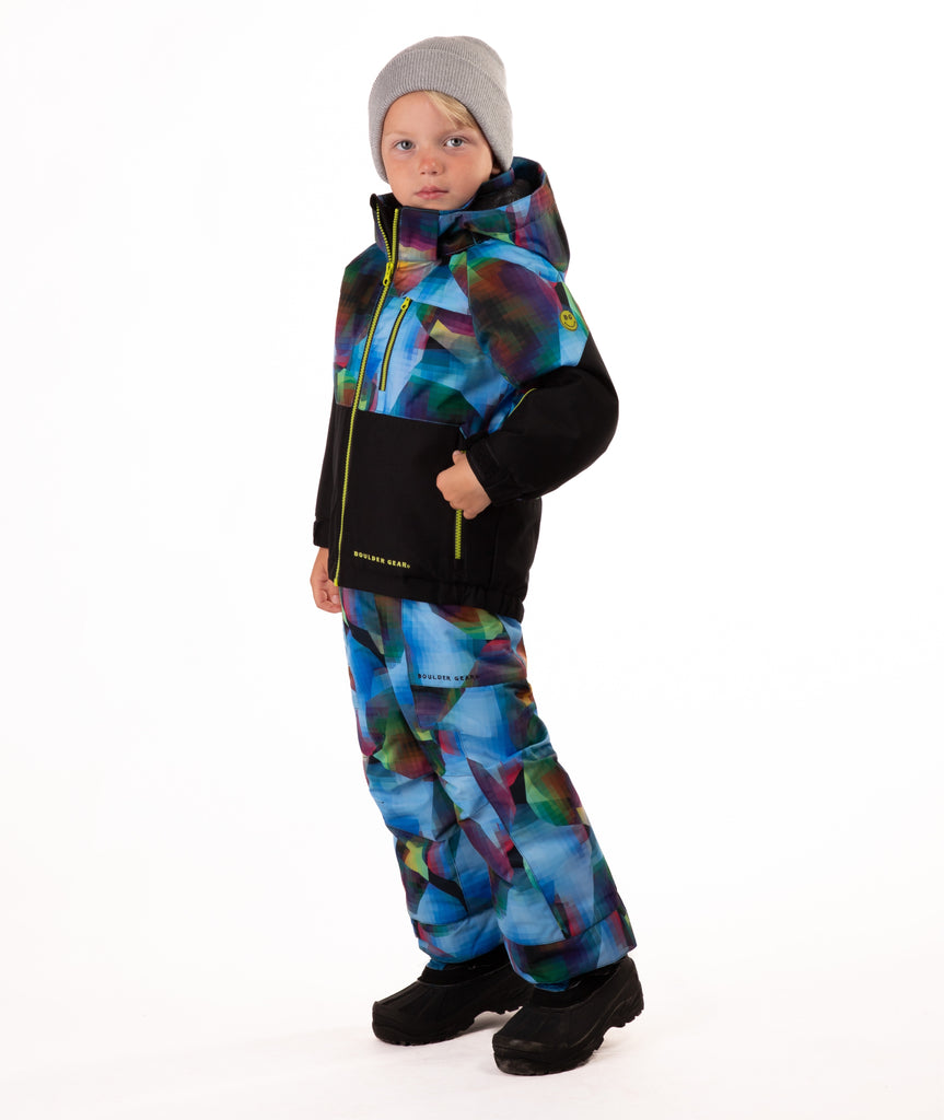 Child wearing a two-tone jacket with black  on the bottom half and multi tone blue pattern top half on a white background