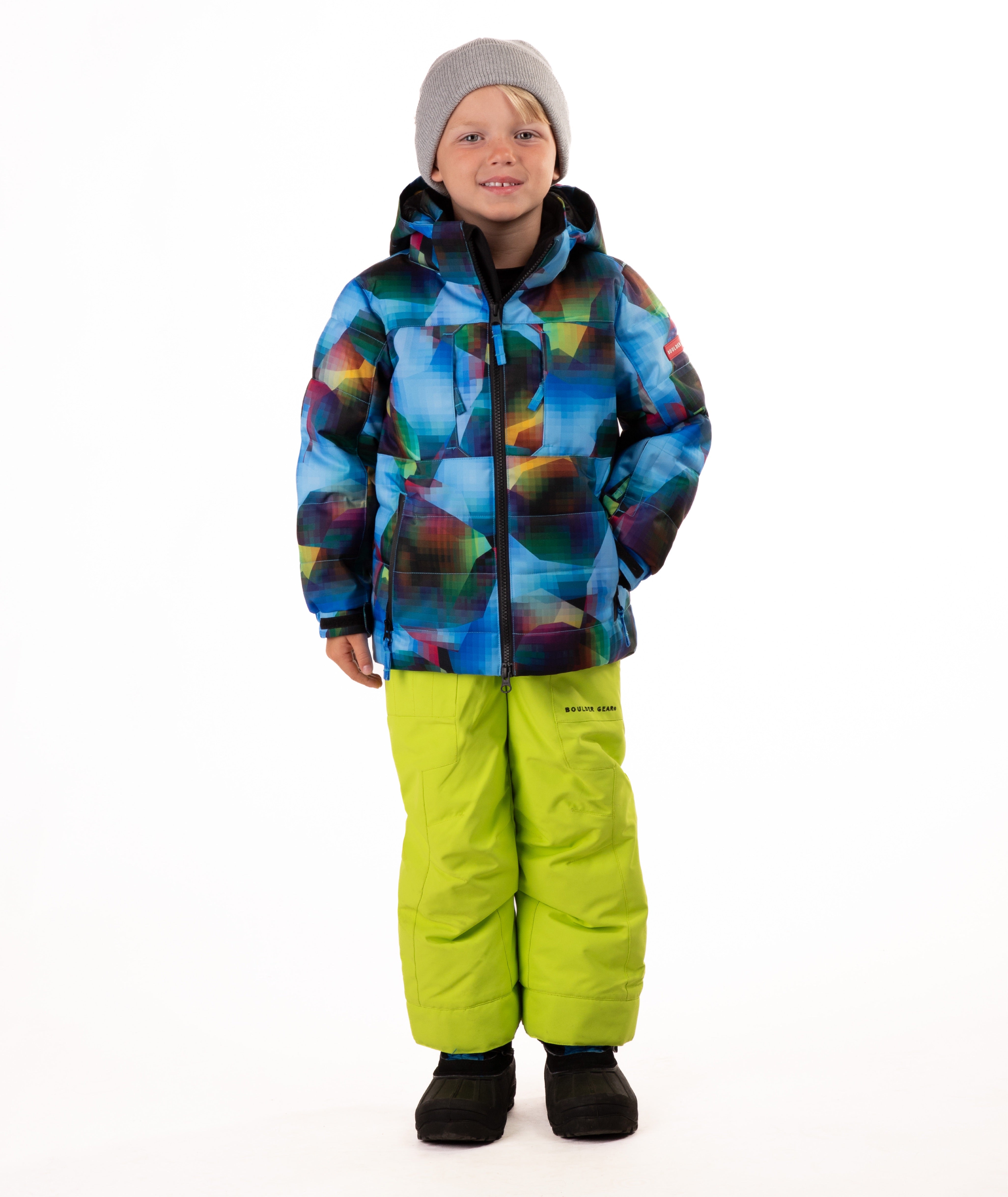 Child wearing a yellow, blue, and black multi color print quilted winter jacket with chest pockets and hand-warmer pockets on a white background