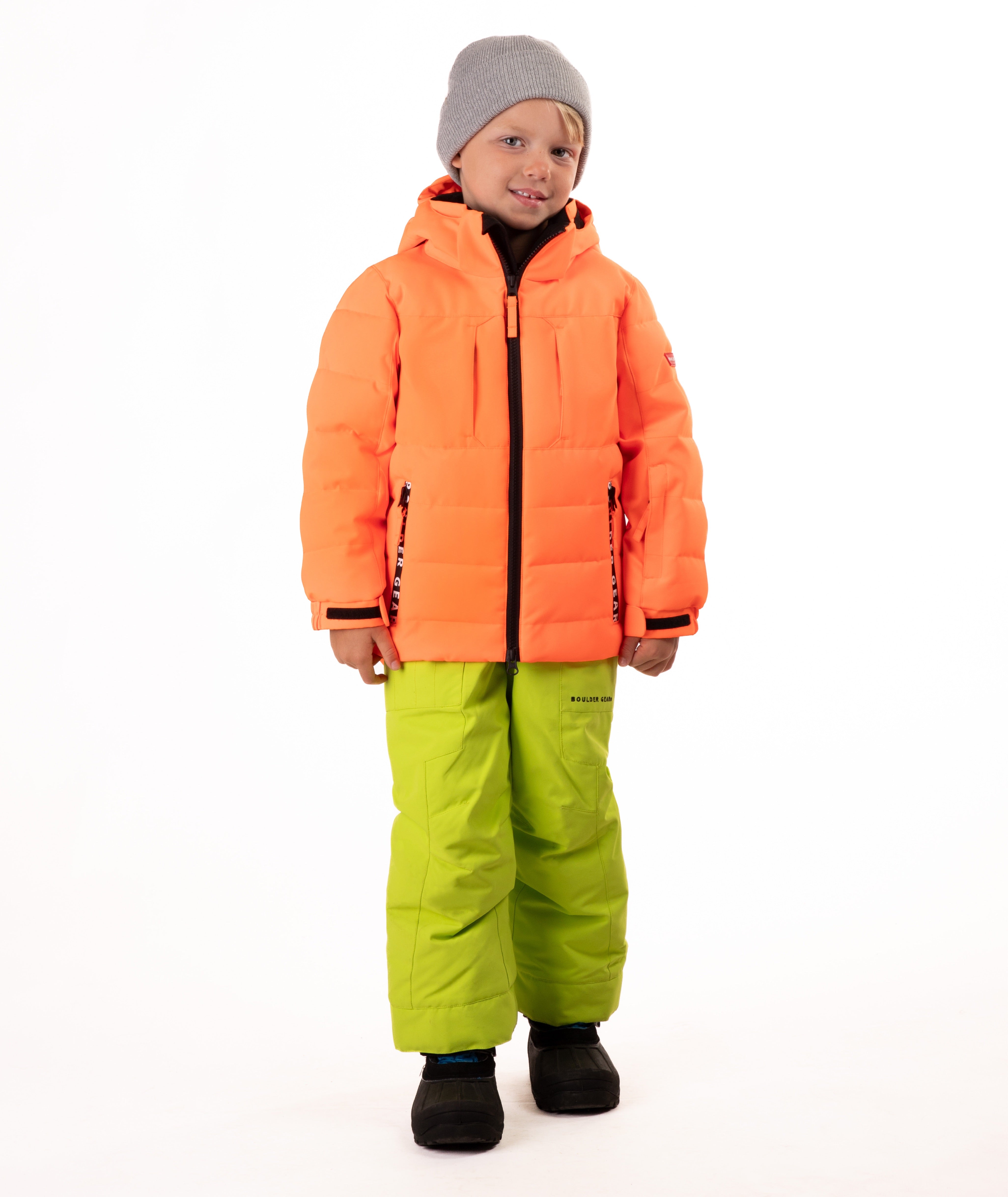 Child wearing a orange quilted winter jacket with chest pockets and hand-warmer pockets on a white background