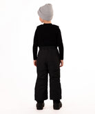 A child wearing black snow bib overalls over a black long-sleeve shirt and black beanie, standing against a plain white studio background.