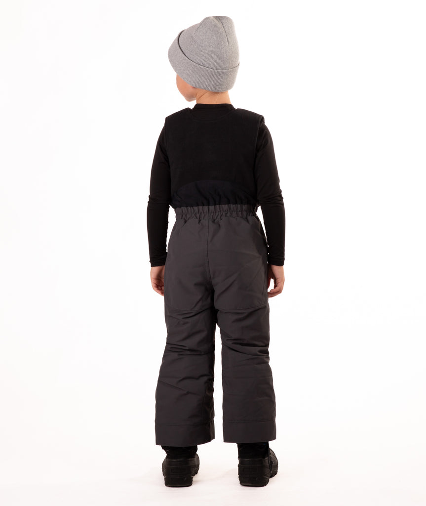 Child wearing dark gray snow bibs on a white background
