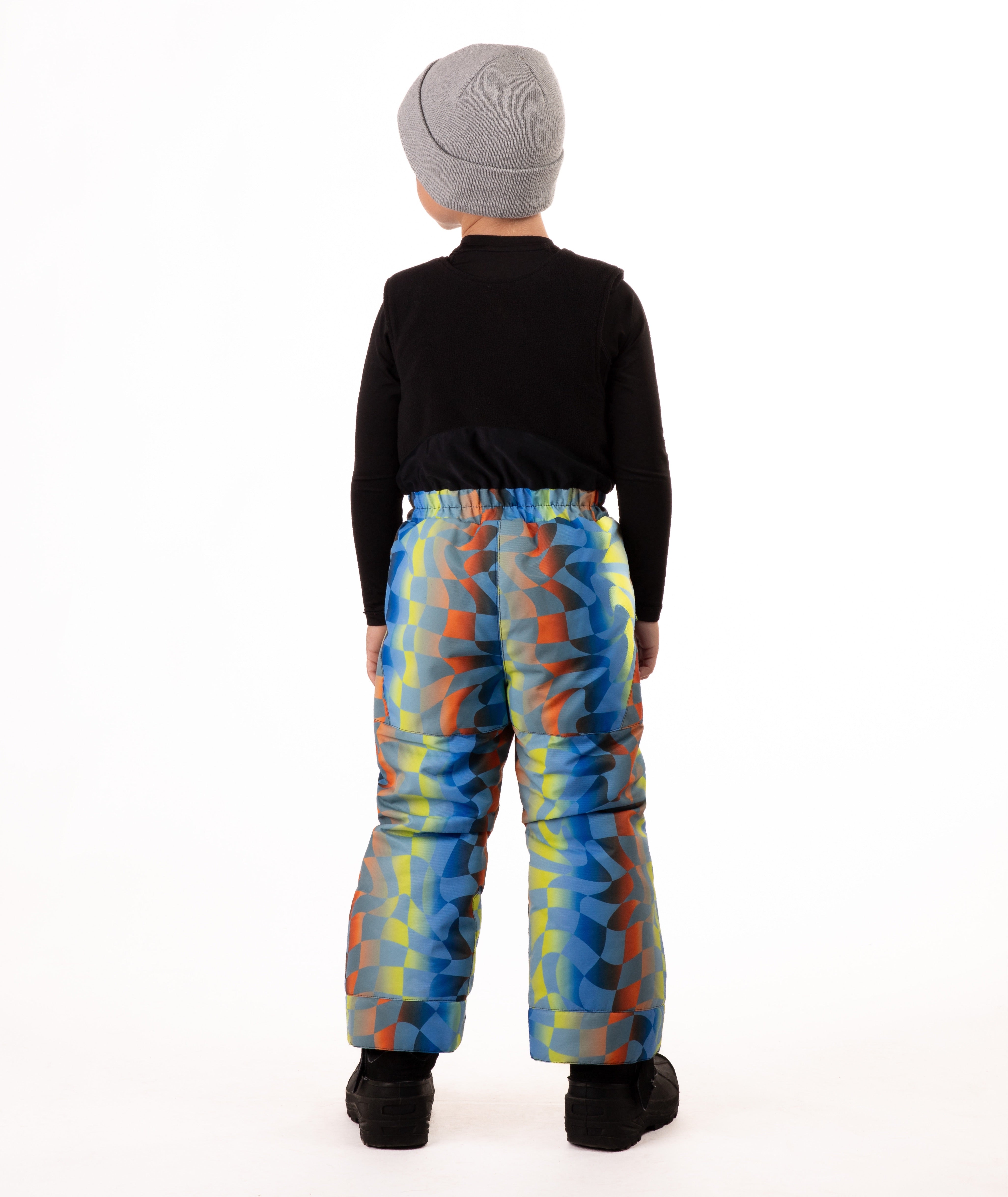 Child wearing colorful geometric print snow bibs on a white background highlighting back of the bib