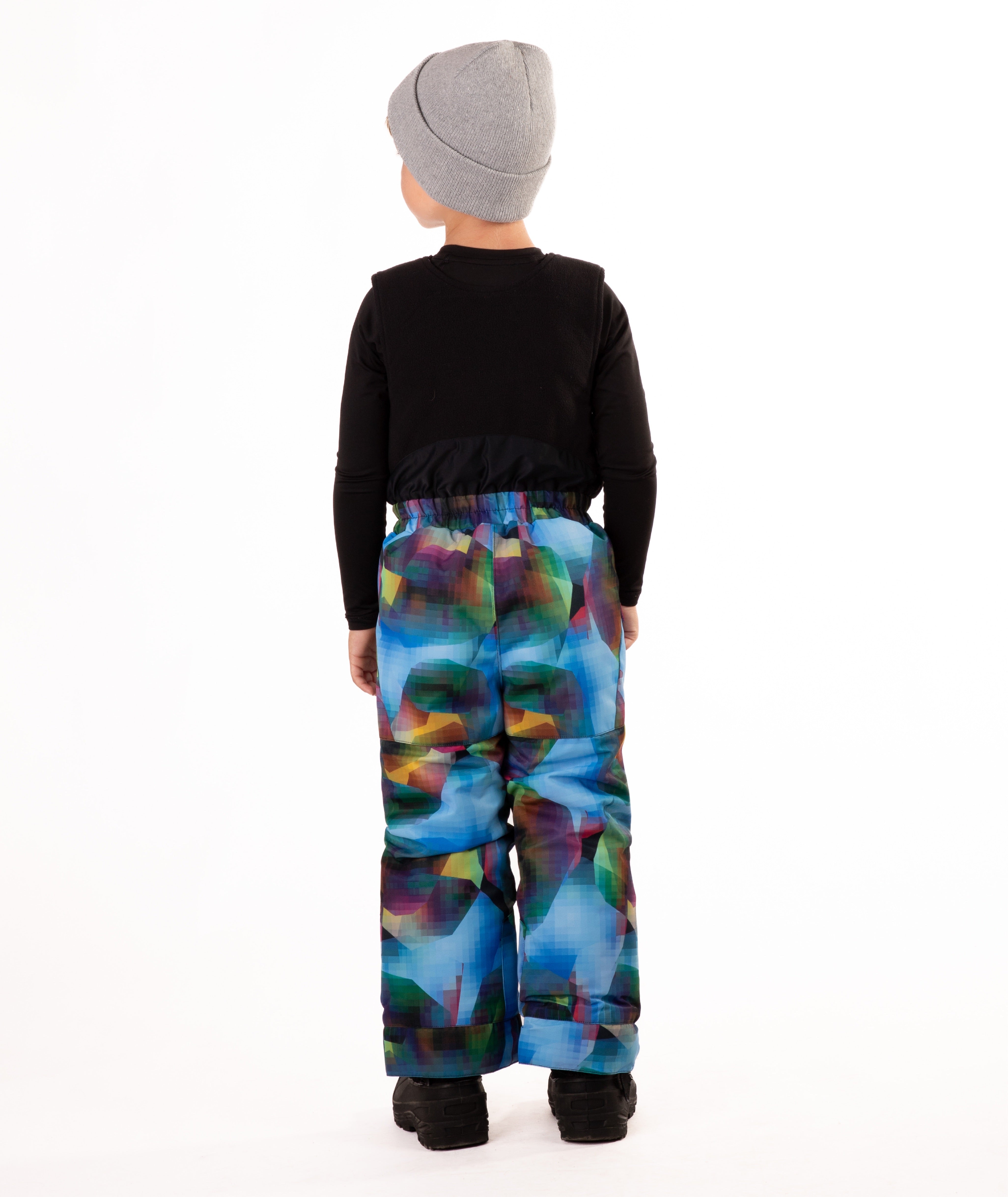 Child wearing colorful geometric print snow bibs on a white background highlighting the back of the bib