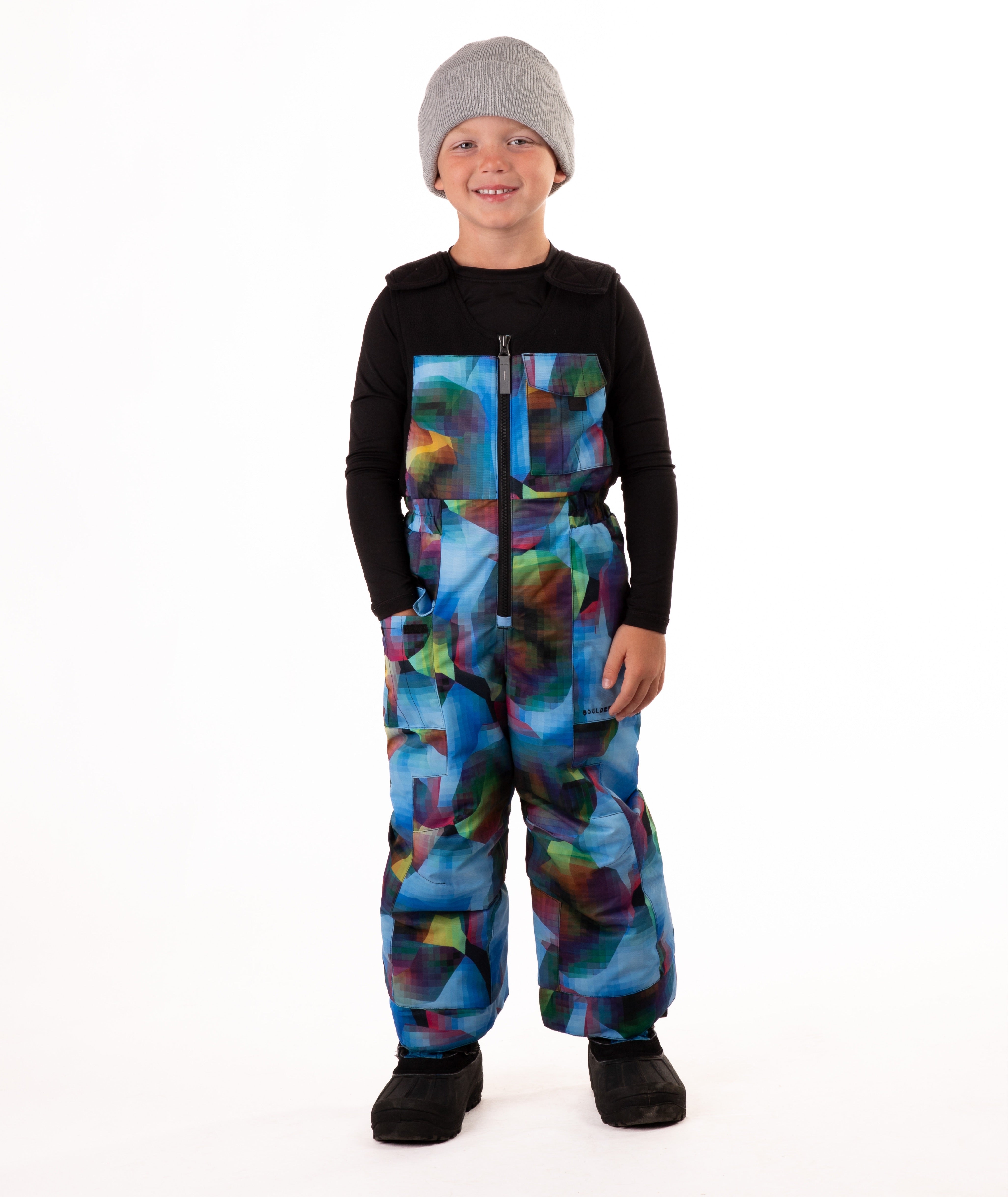 Child wearing colorful geometric print snow bibs on a white background