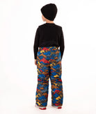 A child wearing a black knit beanie, a black long-sleeve top, and rust colored snow bib overalls, standing against a plain white background.
