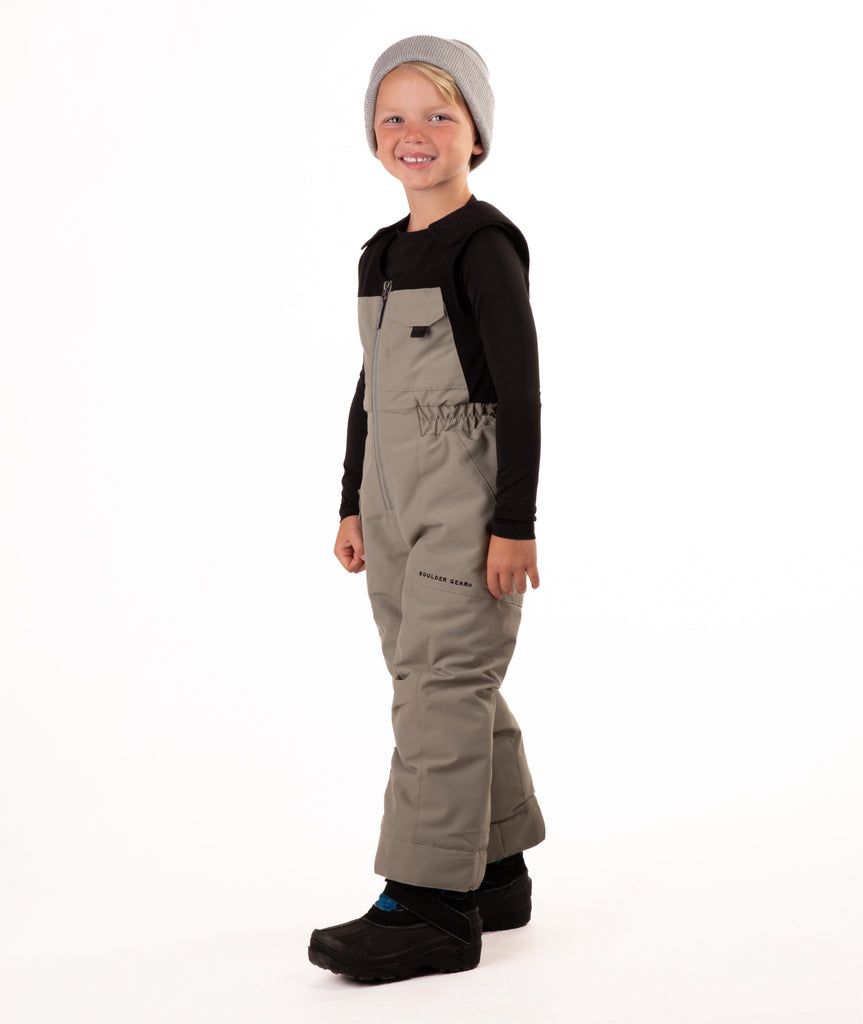Child wearing gray snow bibs on a white background