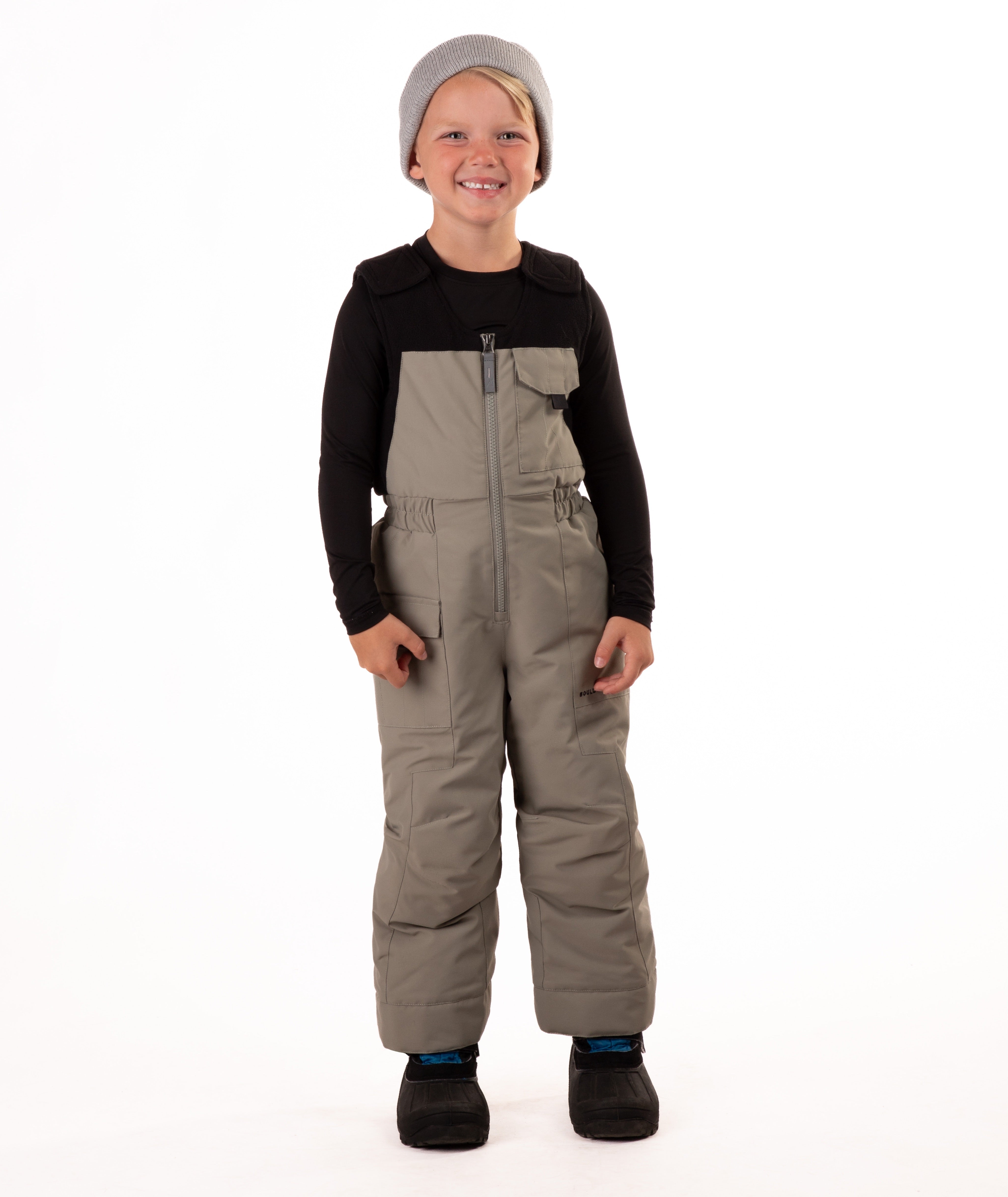 Child wearing beige snow bibs on a white background