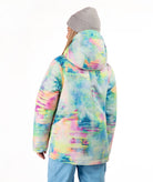 A model shown from the back wearing a hooded snowboard jacket with a vibrant pastel tie-dye pattern in green, blue, pink, and yellow, paired with a gray beanie and light blue pants, on a white background.