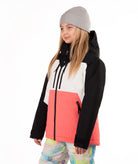 A young girl wearing a color-blocked ski jacket with black, white, and coral pink panels, a gray beanie, and tie-dye snow pants, photographed against a solid white background.
