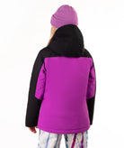 A person shown from the back wearing a color-blocked ski jacket with a bright purple body and black sleeves and hood, along with a matching purple beanie and patterned pants, against a plain white background.