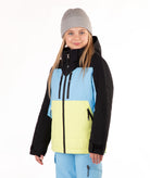 A young girl wearing a color-blocked ski jacket with black sleeves, a light blue upper chest, and a bright yellow lower front panel, paired with light blue ski pants and a gray beanie, against a plain white background.