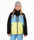 A young girl wearing a color-blocked ski jacket with black sleeves, a light blue upper chest, and a bright yellow lower front panel, paired with light blue ski pants and a gray beanie, against a plain white background.