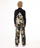 back of boy wearing camouflage bibs and black top on a white background