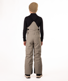 back of boy wearing beige bibs and black top on a white background