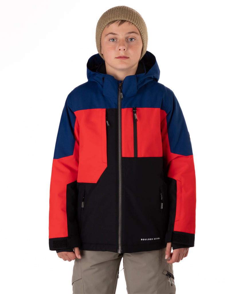 Boy wearing a colorful jacket with black, blue, and red sections on a white background