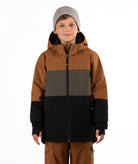 A child wearing a color-blocked ski jacket in brown, green, and black, paired with brown pants and a gray beanie, photographed against a solid white background.