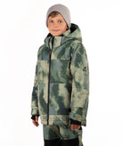 A child wearing a camouflage-patterned ski jacket and matching pants with a gray beanie, standing against a plain white background.