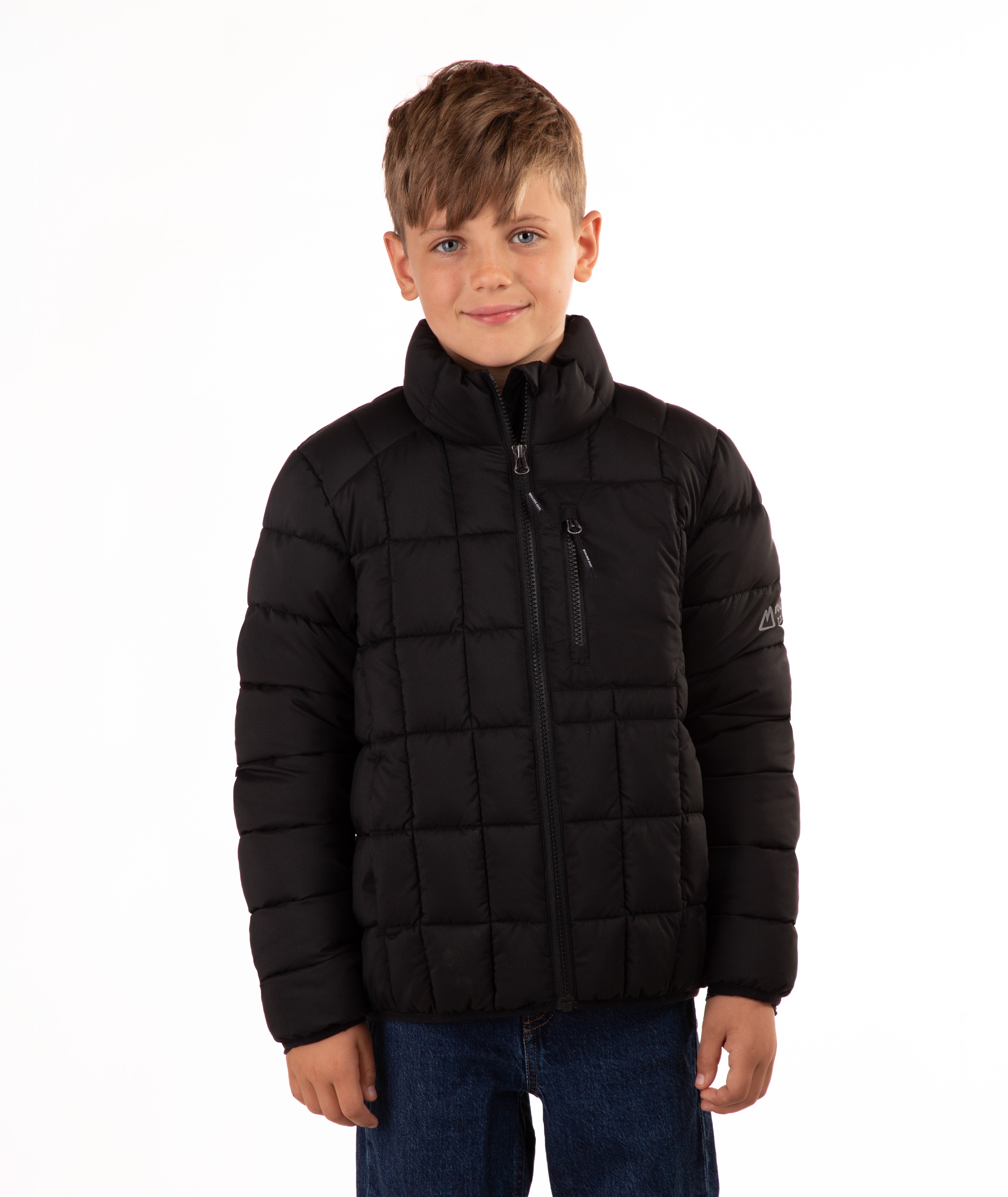 A young boy wearing a black quilted puffer jacket with a stand-up collar and front zipper, paired with blue jeans, photographed against a solid white background.