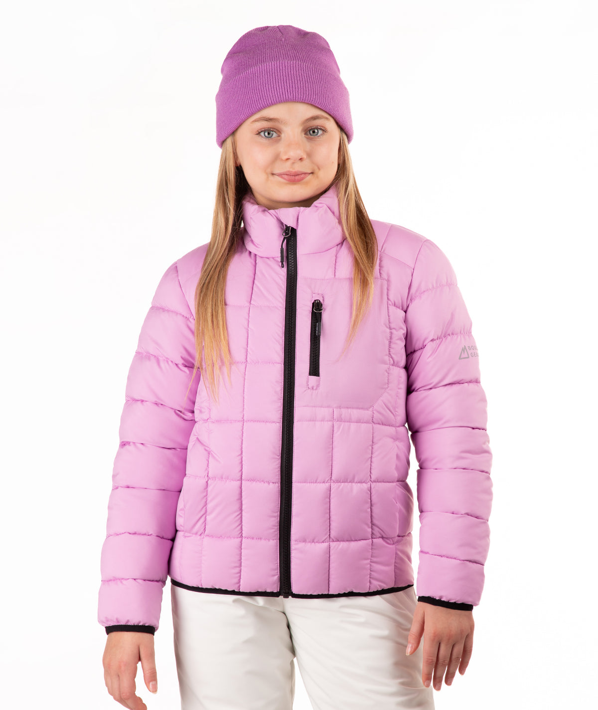 A young girl wearing a light purple puffer jacket, a matching pink knit beanie, and white pants, standing against a plain white background.