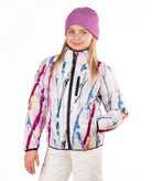 A young girl wearing a white puffer jacket with a colorful paint-splatter pattern, a purple knit beanie, and white pants, photographed against a plain white background.