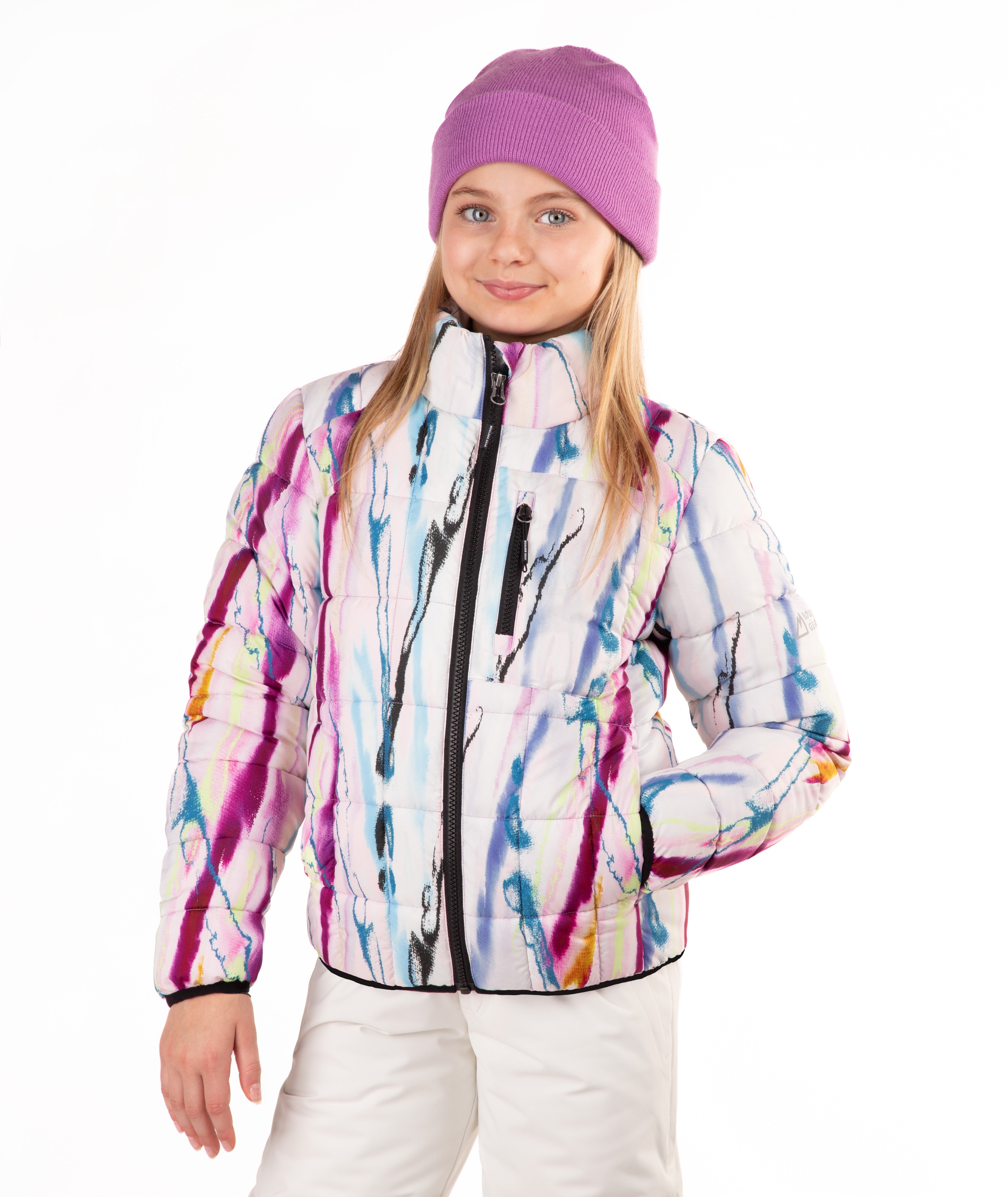 A young girl wearing a white puffer jacket with a colorful paint-splatter pattern, a purple knit beanie, and white pants, photographed against a plain white background.