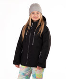 A young girl wearing a black ski jacket, a gray beanie, and colorful tie-dye snow pants, standing against a solid white background.