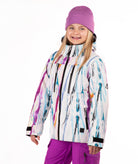 A child wearing a colorful abstract print ski jacket, a purple knit beanie, and purple ski pants, standing against a plain white studio background.