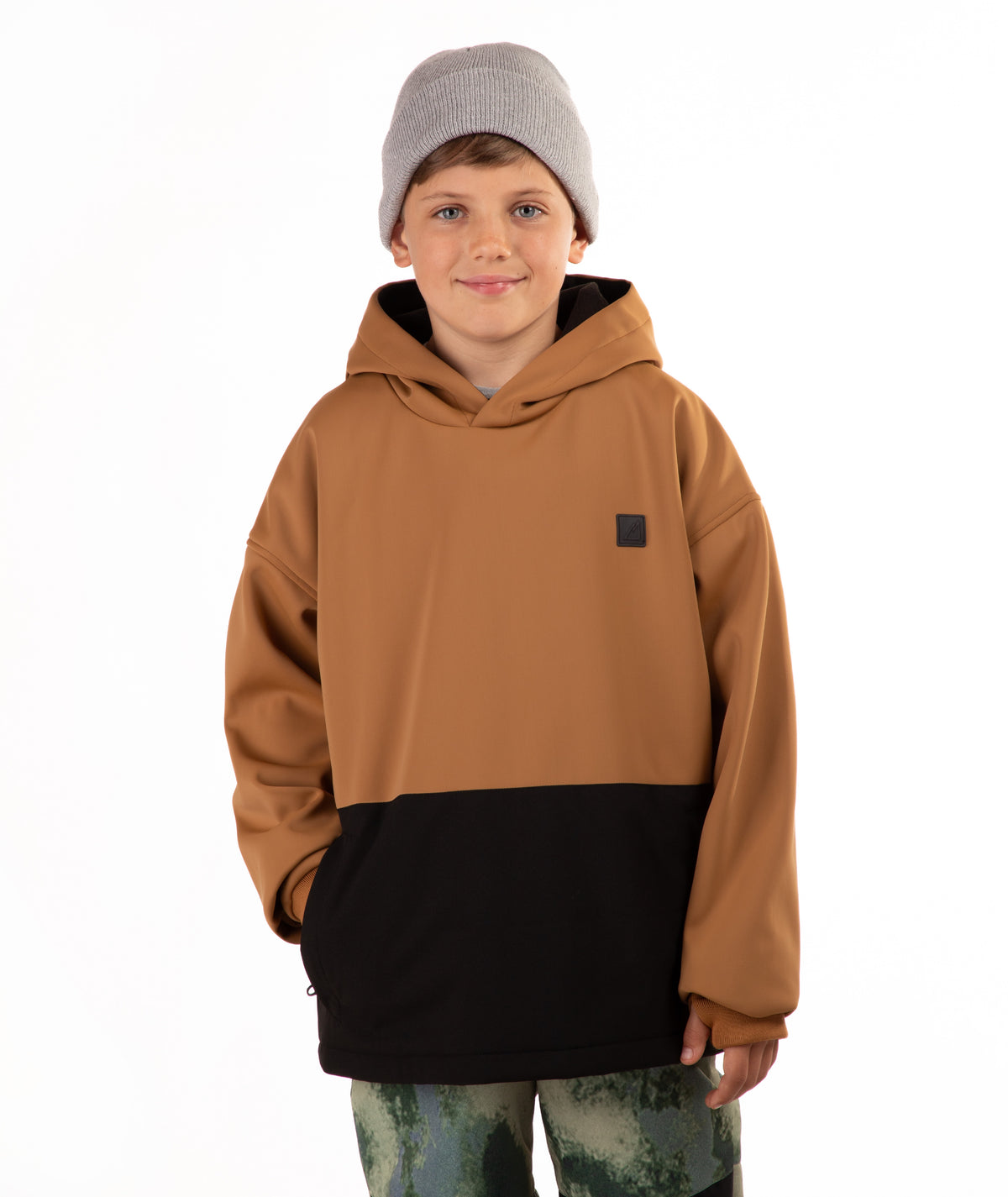 A child wearing a color-blocked hoodie with a brown upper half and black lower half, paired with a gray beanie and camouflage pants, photographed against a plain white background.